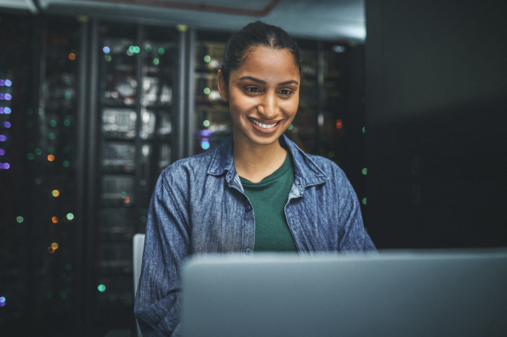female IT technician in a server room and using a laptop